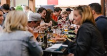 Group of people seated around a dinner table, laughing and talking.